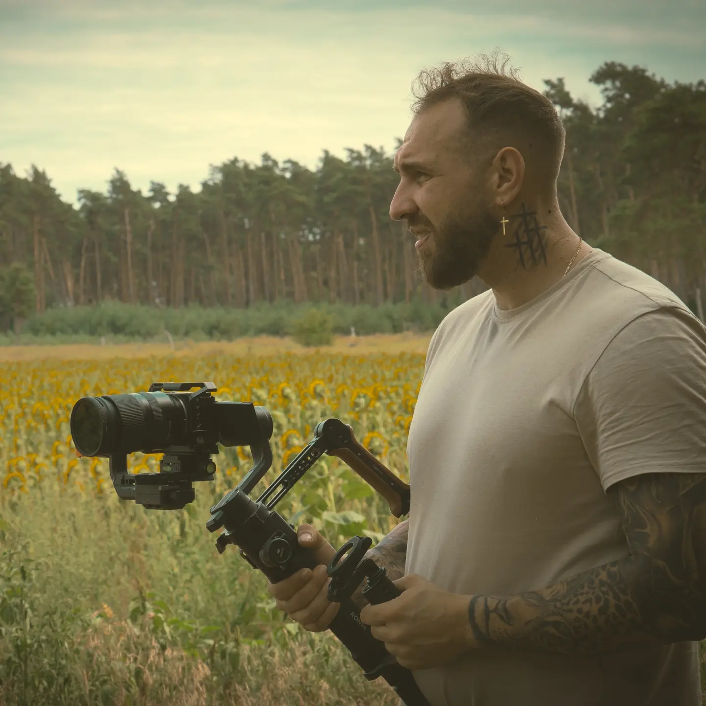 Mężczyzna z gimbalem i kamerą na tle lasu i polne pola słoneczników – Obiektywni Studio